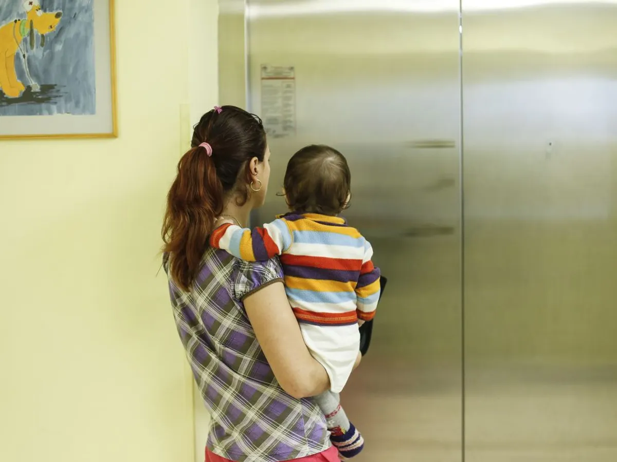 Mama cu copil in brate langa lift
